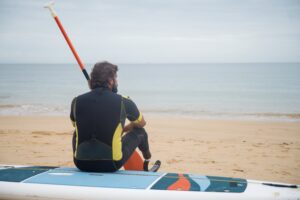 Man in paddle-boarding equipment looking out into the ocean